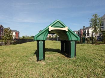 a dog house in a grassy area with houses in the background